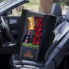 Boxed arrangement of red roses with a wine bottle and card in a car seat