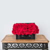 Red roses arranged in a black box on a wooden table