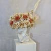 Floral crown on a white bust with cream and peach blooms