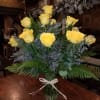 Yellow roses arranged in a clear glass vase with a white ribbon