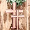 Wooden cross display with green foliage on a rustic wood backdrop