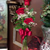 Three beautiful roses in a bud vase with filler flowers, greens, and