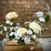 Cream roses and white daisies in a clear vase with pastel filler flowers