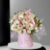 Pink and white bouquet in a pink hatbox with baby-themed decorations