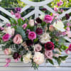 Mixed bouquet of pink, white, and burgundy flowers on a white bench