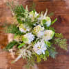 White floral bouquet with green accents and pine branches