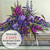 Long purple and pink floral casket spray arranged on a silver casket.