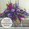 Long purple and magenta floral casket spray arranged on a silver casket lid