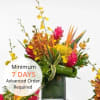 Tall tropical arrangement with yellow, orange, and pink flowers in a green cylinder vase