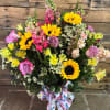 Bouquet of sunflowers, pink roses, and mixed blooms in a glass vase