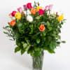 Mixed roses in a clear glass vase with dense greenery