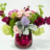 Mixed bouquet in a magenta glass vase with pink, purple, and green blooms