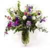 Mixed purple, pink, and white flowers in a clear glass vase