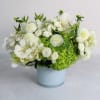 White floral arrangement in a pale blue vase with green accents