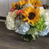 Hydrangea, sunflowers, and orange roses arranged in a vase 