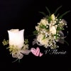 White rose boutonniere and matching wrist corsage with white ribbons on a black background.