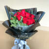 Bouquet of red roses wrapped in black paper with a silver ribbon