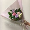 Pastel bouquet of pink and lavender roses wrapped in pink paper with a satin ribbon bow