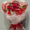Bouquet of red roses wrapped in pink and white mesh with a red ribbon
