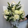 White bouquet with lilies, roses, and hydrangea wrapped in white paper