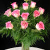 Pink roses arranged in a clear glass vase with airy greenery