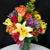 Mixed bouquet with lilies, roses, and daisies in a glass vase