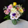 Mixed bouquet of roses, daisies, and gerbera daisies in a glass vase