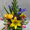 Tall mixed bouquet in a glass vase with yellow lilies and purple irises