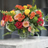 Mixed roses in a clear glass vase with greenery
