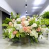 Large floral arrangement with white and blush roses in a square vase