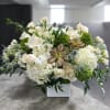 White floral arrangement with succulents in a square vase