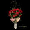 Red roses and pink hydrangeas in a tall white vase