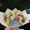 Colorful bouquet of roses, hydrangeas, and carnations wrapped in white paper with a pink bow