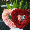 Heart-shaped rose arrangements in pink and red with tall green leaves behind them