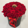 Red roses arranged in a black hatbox with a red ribbon