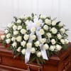White rose casket spray with a white ribbon on a wooden casket