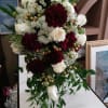 Tall bouquet of white and burgundy flowers with trailing greenery