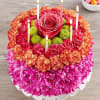 Round floral cake with candles and a pink rose center