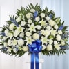 Large white floral standing spray with a blue ribbon bow