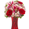 Red roses and pink lilies arranged in a red glass vase