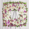 Floral standing wreath with white lilies, daisies, and pink blooms on an easel