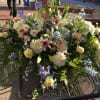 Large mixed floral arrangement with white lilies, roses, and blue flowers