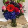 Colorful mixed bouquet in a glass vase with hydrangeas, roses, and a gerbera daisy