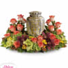 Floral urn arrangement with coral roses and purple orchids around a silver urn