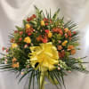 Large mixed flower arrangement with a yellow bow in a clear vase