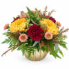 Yellow and burgundy flowers arranged in a gold pumpkin vase