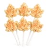 Six maple leaf-shaped cake pops with orange sprinkles on white sticks