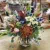 Mixed bouquet in a clear glass vase with daisies and spiky blue flowers