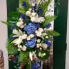 Tall blue and white floral arrangement with lilies, roses, and hydrangeas