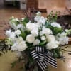 White floral arrangement with a striped ribbon in a low container